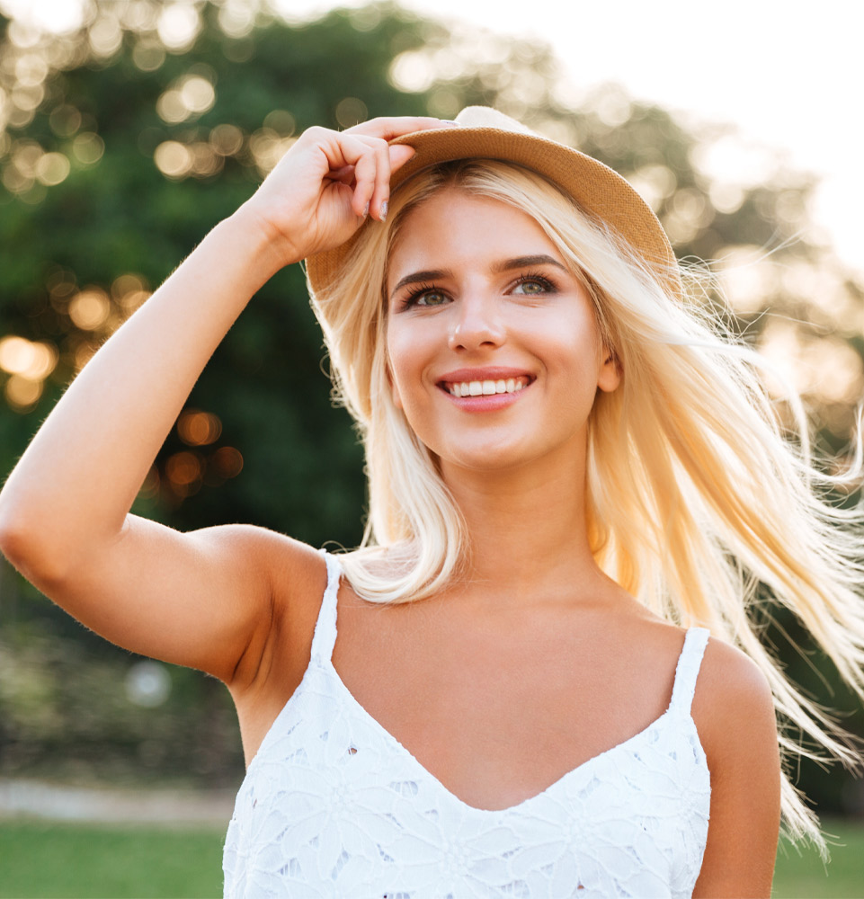Nice lady smiling looking to the side outside because she went to Dental Care and Implants