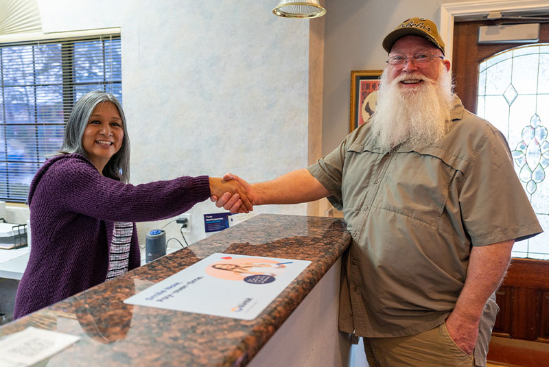 patient and staff member shaking hands at the front desk of the dental center
