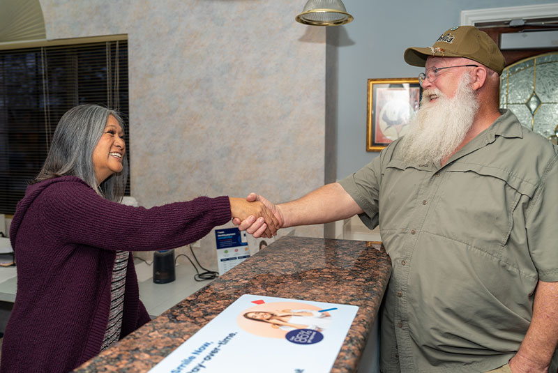 patient and staff member shaking hands at the front desk within the dental center